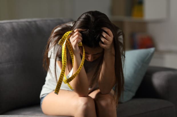 Mulher frustrada com fita métrica na mão antes de emagrecimento saudável