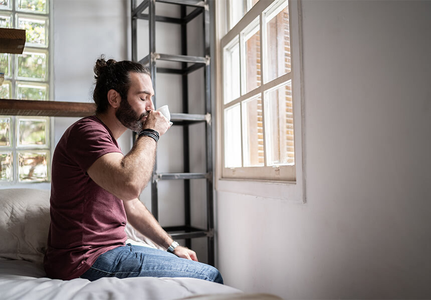 homem bebendo café em seu quarto de forma relaxante 