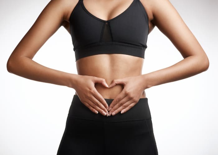 Mulher com intestino saudável fazendo coração com as mãos na barriga