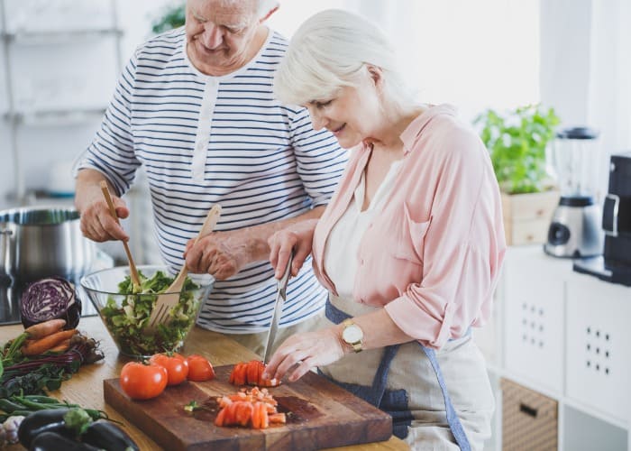 Casal cozinhando alimentos saudáveis que ajudam a evitar má perda de peso em idosos