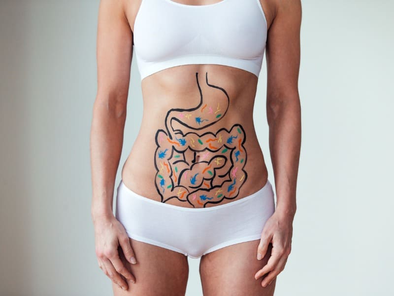 Hábitos saudáveis impactam nos cuidados com o estômago Mulher de top com funcionalidade e cuidados com o estômago desenhado na barriga