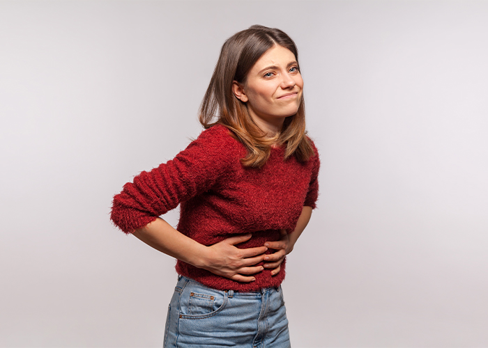 mulher com dor de barrriga emá digestão devido ao stress ao comer com balão spatz