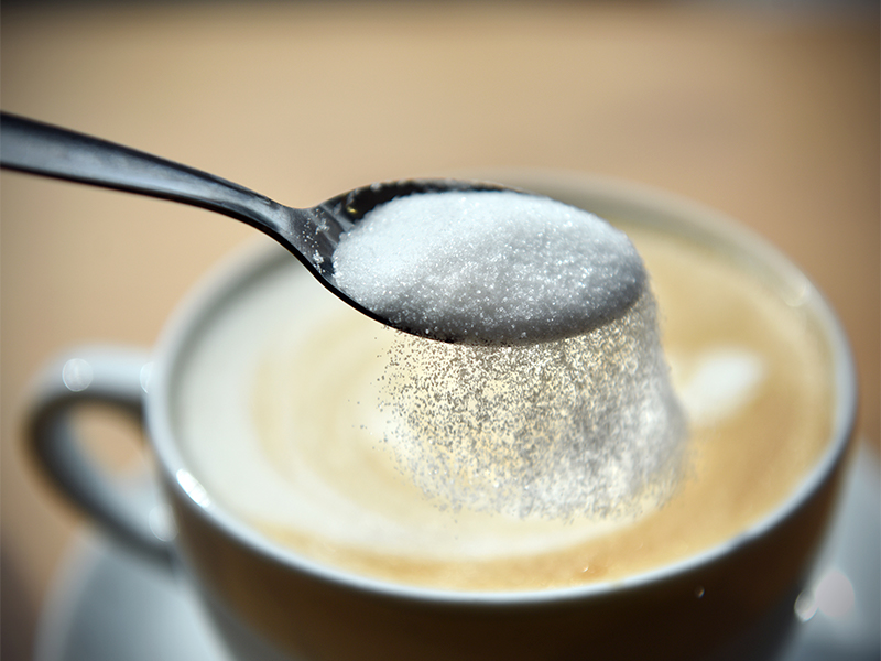 xícara de café com açúcar sendo despejado por uma colher em uma dieta com balão spatz3